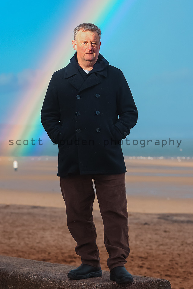 Kevan Christie author portrait on Portobello beach with a rainbow